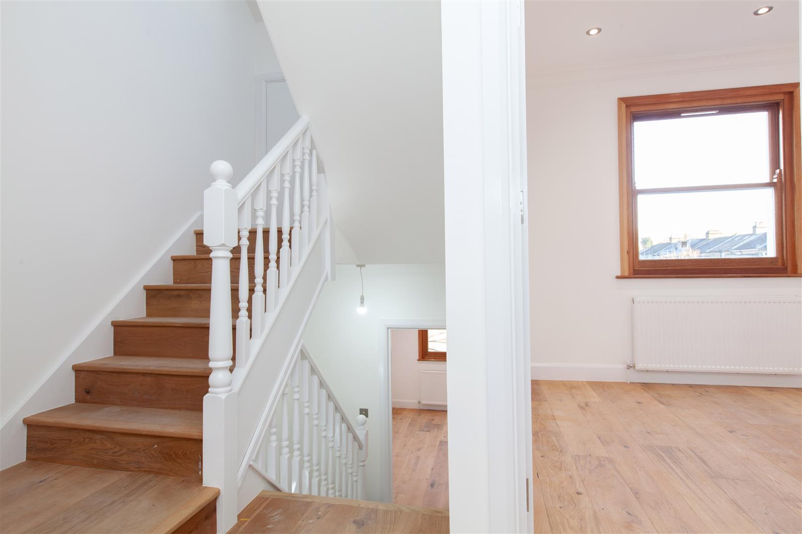 A picture of newly refurbished staircase with natural wood stairs leading to the lower ground level of Victorian townhouse.